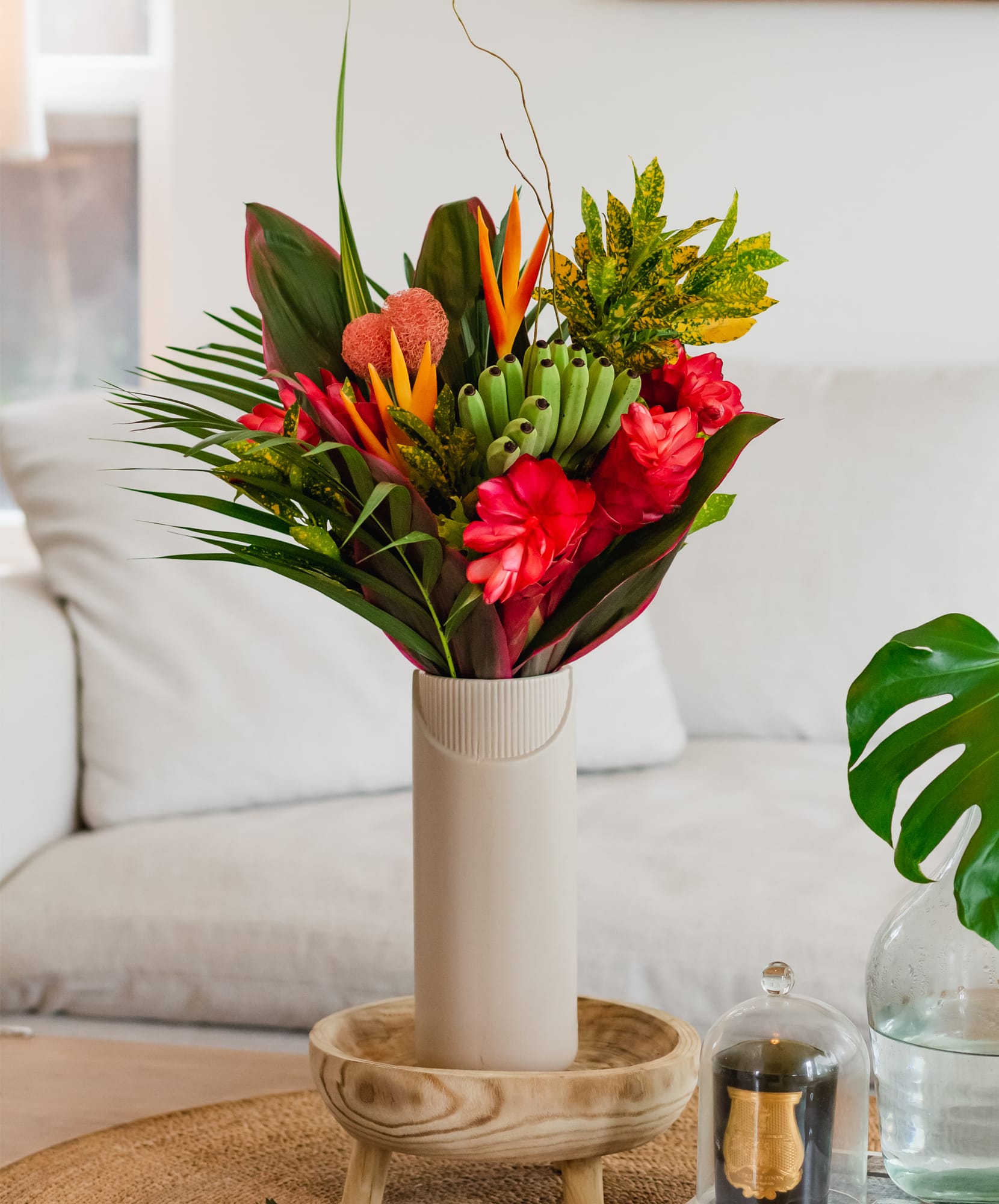Vibrant tropical flower arrangement featuring red and orange blooms in a modern vase.