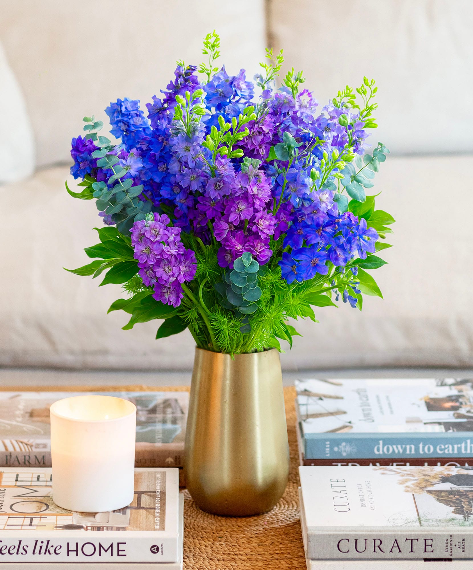 Vibrant purple floral arrangement featuring delphiniums and greenery in a stylish vase.