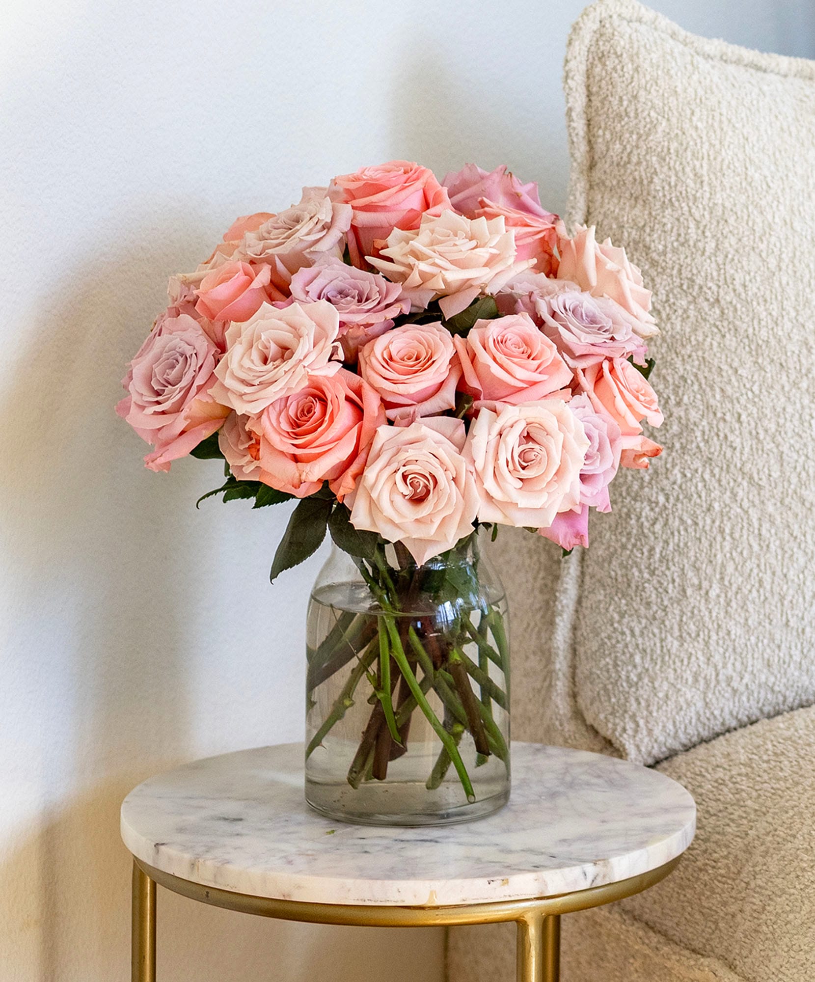Elegant bouquet of pink and peach roses in a glass vase, perfect for home décor.